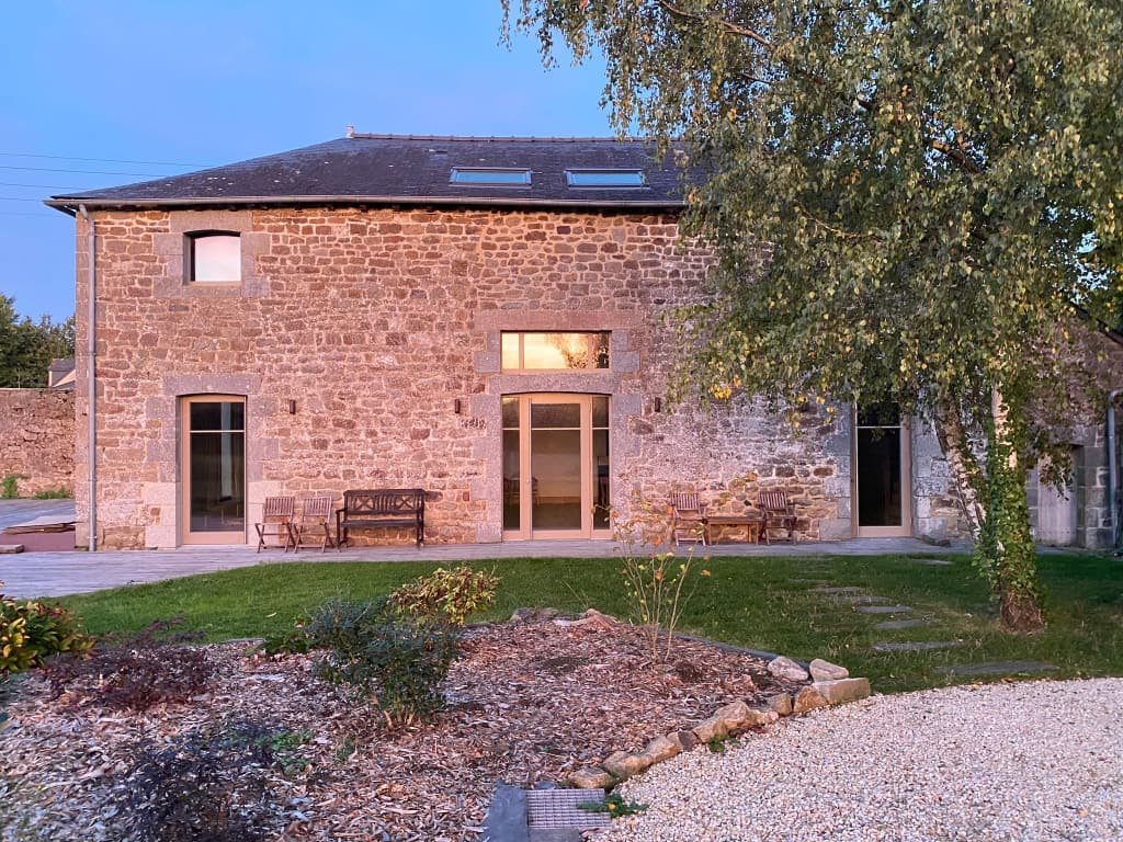 Façade en pierre de l'Espace Les Passages Suspendus à Bazouges-sous-Hédé, sa terrasse et son jardin